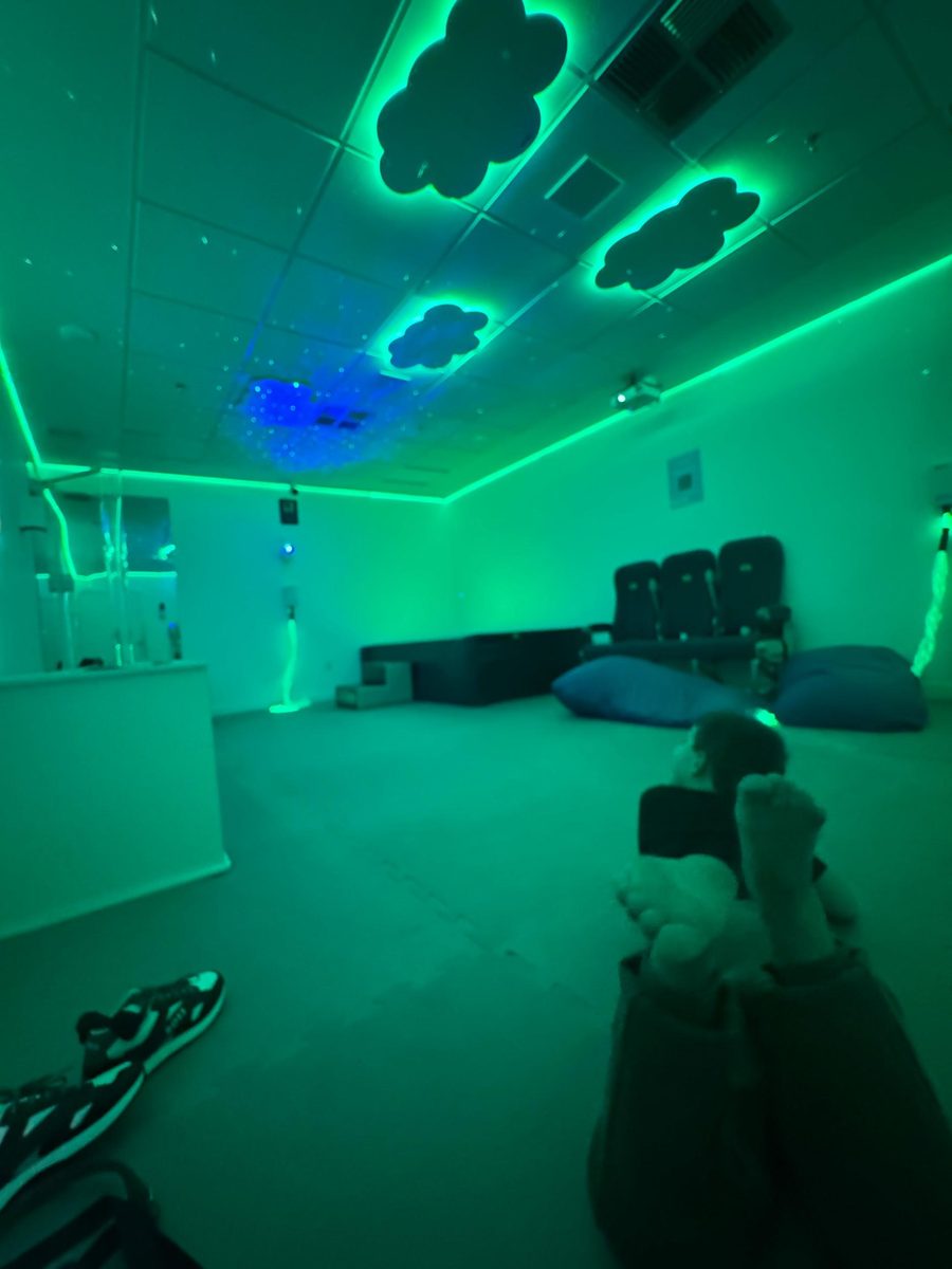 Sala multissensorial com iluminação verde e pufes para acolhimento